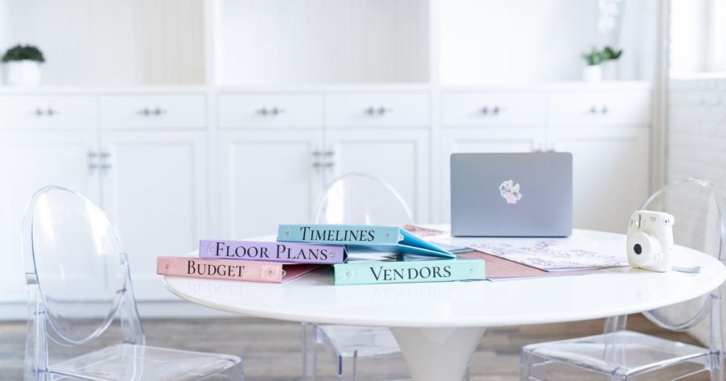 A desk with wedding planning binders for wedding vendors, timelines, floor plans, and budgets. This photo shows  planning for any wedding day emergencies with a wedding emergency kit.