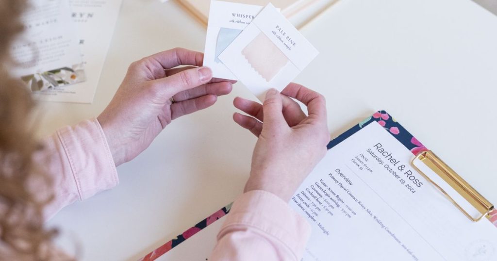 wedding planner looking at color pallete swatches with a checklist on a clipboard, to show preparation for wedding day emergencies.