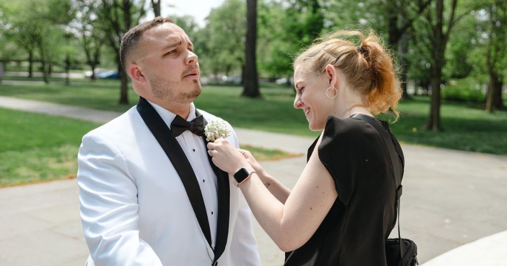 Photo of wedding planner adjusting groomsmen by placing a pin on the tux from her wedding day emergency kit. 