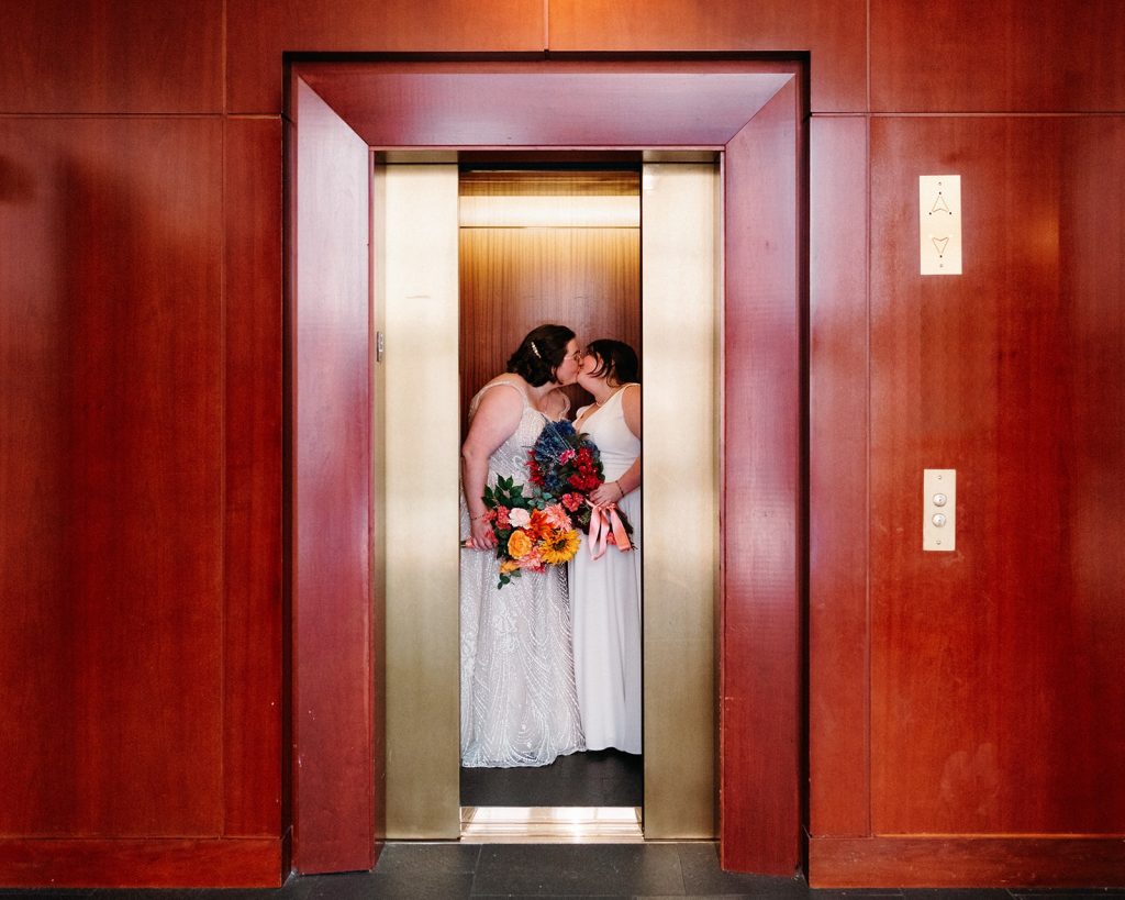 Brides sharing a kiss in the elevator at the Ritz-Carlton Georgetown before their DC Pinstripes wedding