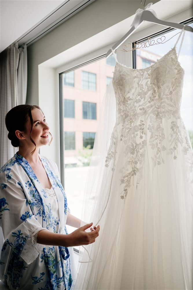 Bride looking at her wedding dress hanging in the window