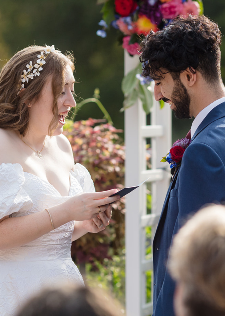 newlyweds stand at the front of the aisle reading vows to each other