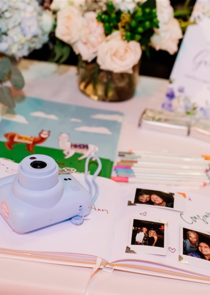 a polaroid camera next to a wedding guest book filled with polaroid photos