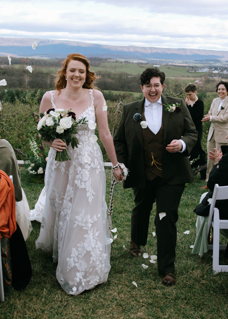 a couple recesses from their wedding ceremony as guests throw flower petals at showalters orchard