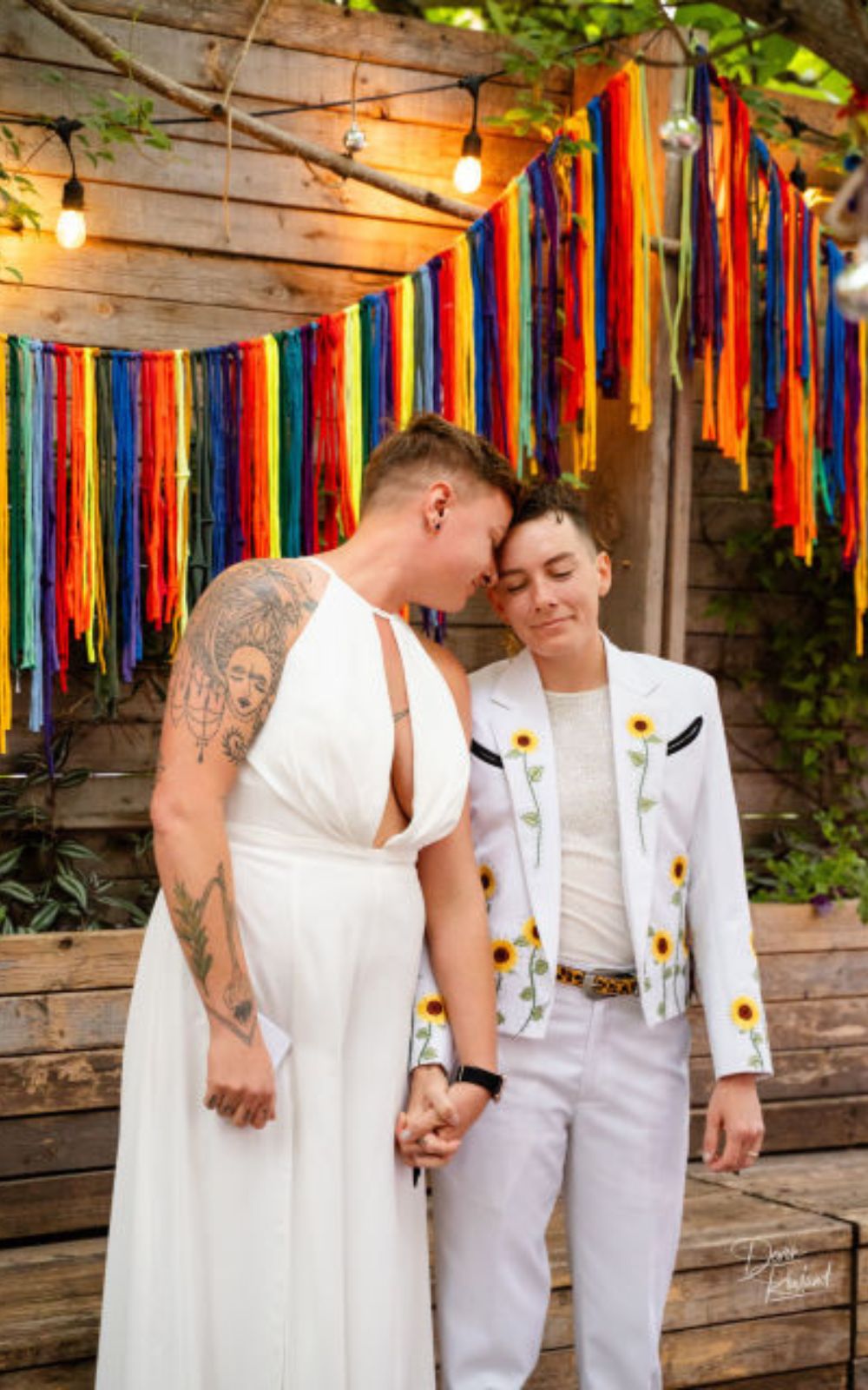Two newlyweds, one in a white dress and one in a white suit, hold hands at their Baltimore wedding