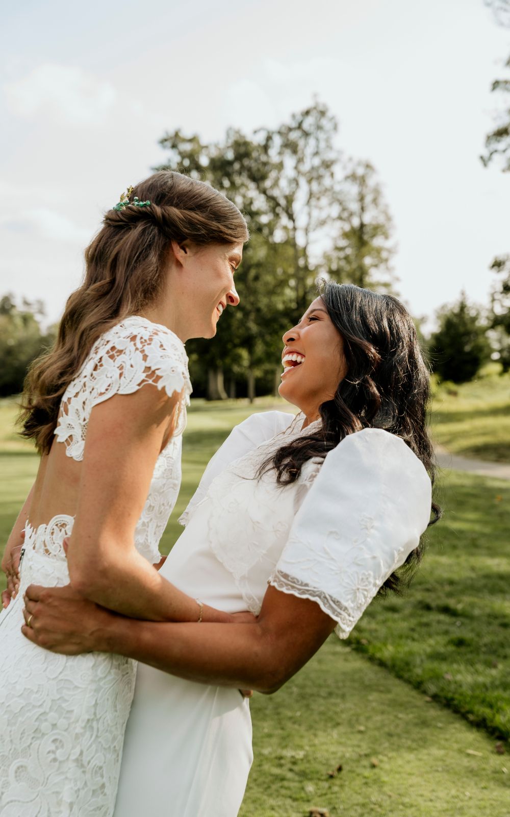 Two brides in white dresses smile at each other at Westfields Golf Club