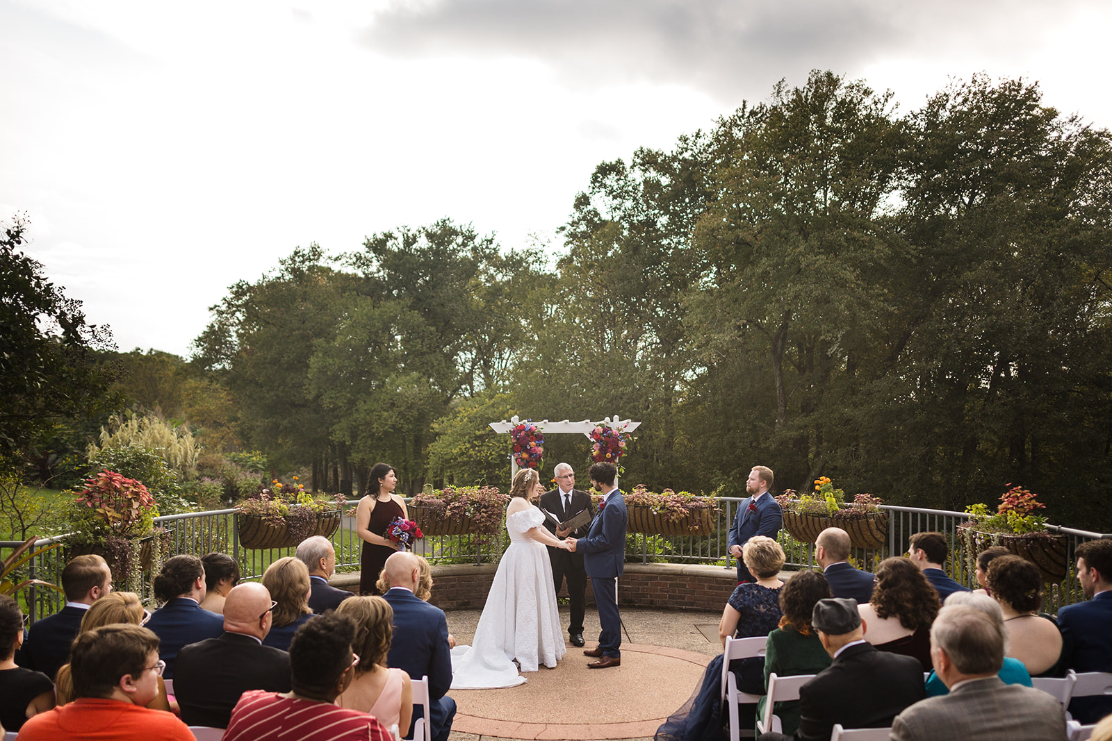 Couple on balcony doing vows and holding hands while guests look on at them