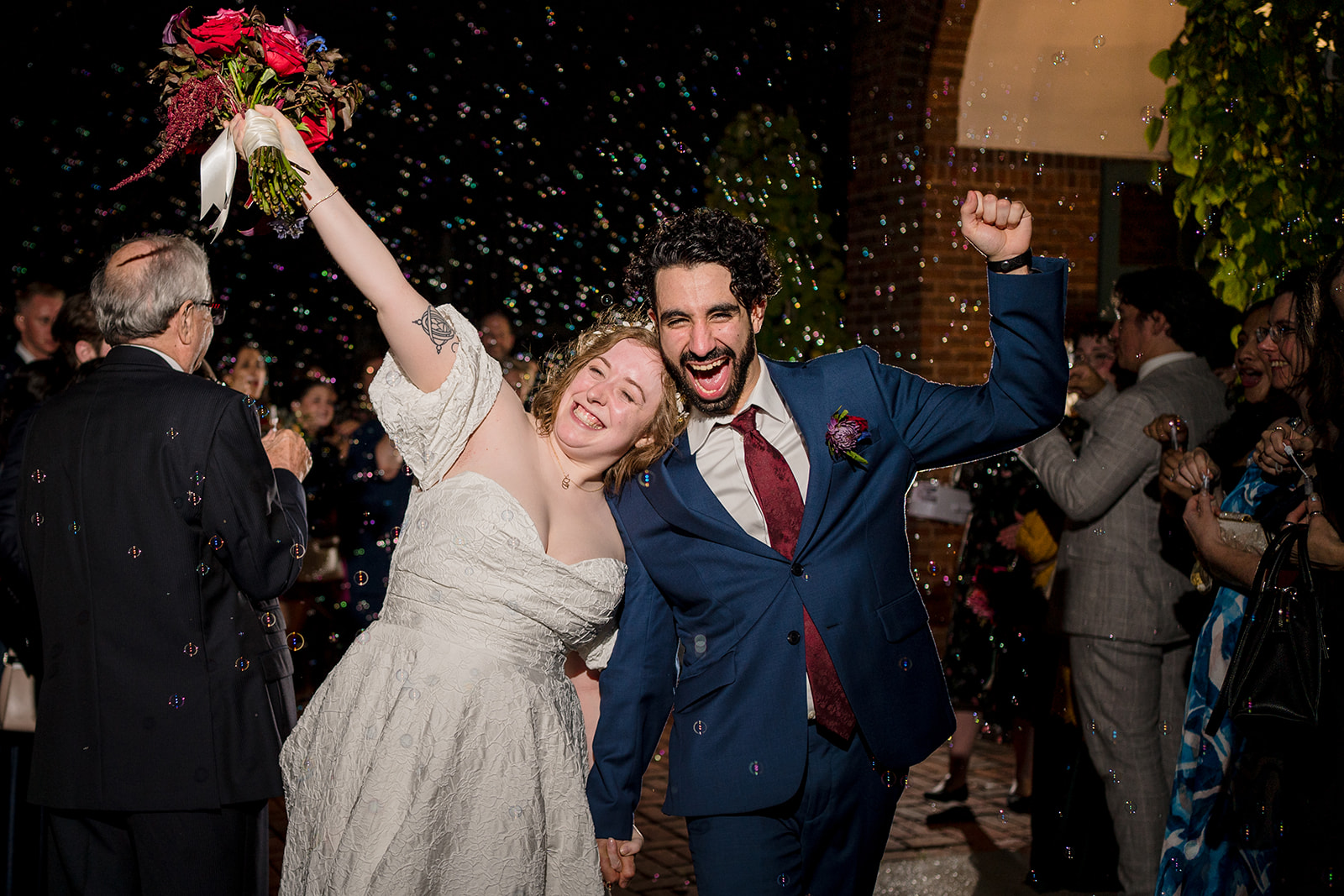 Couple holding hands while doing a bubble exit out of the venue with other hands raised in the air