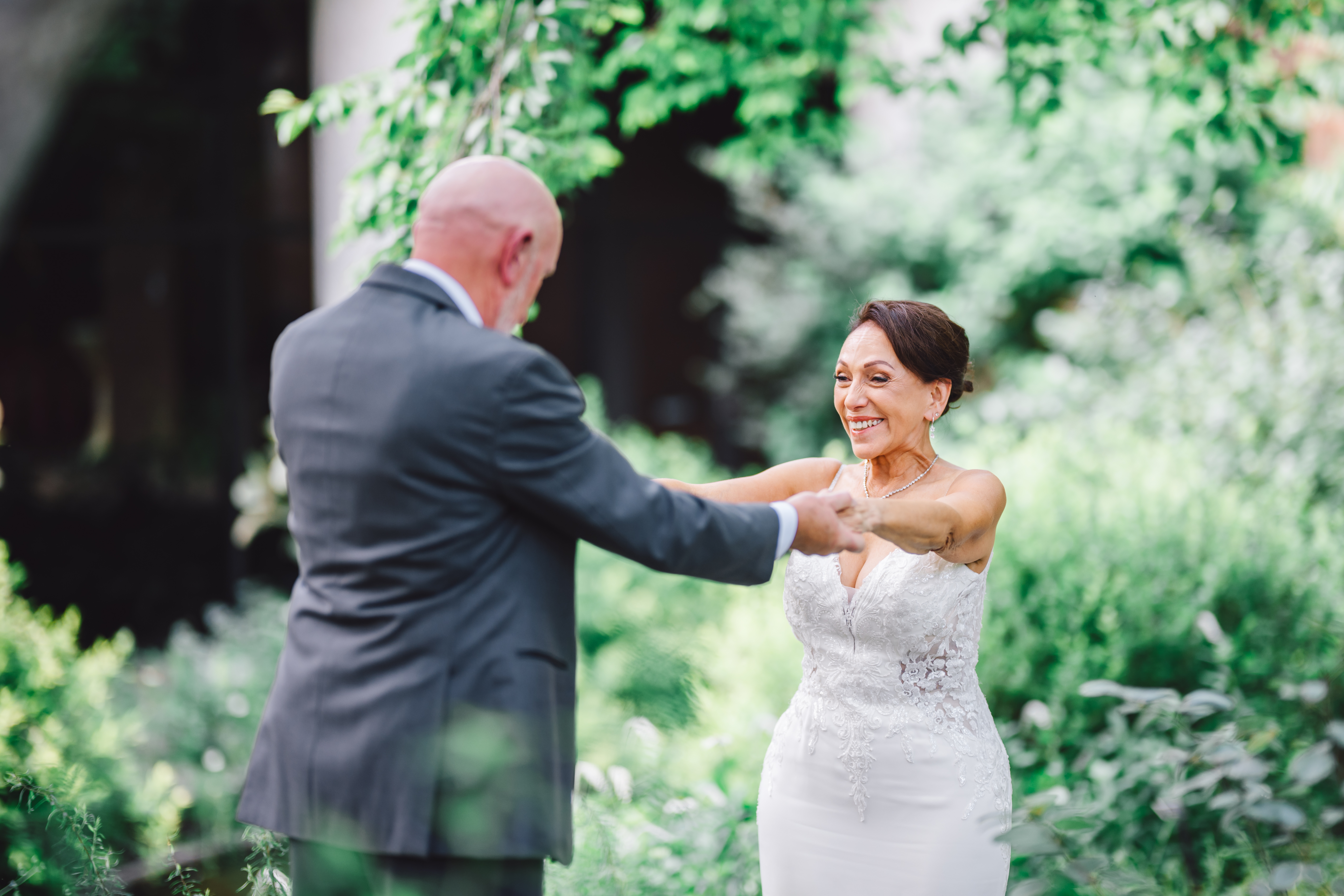 couple portrait with there arms extended out to hug one another in the gardens