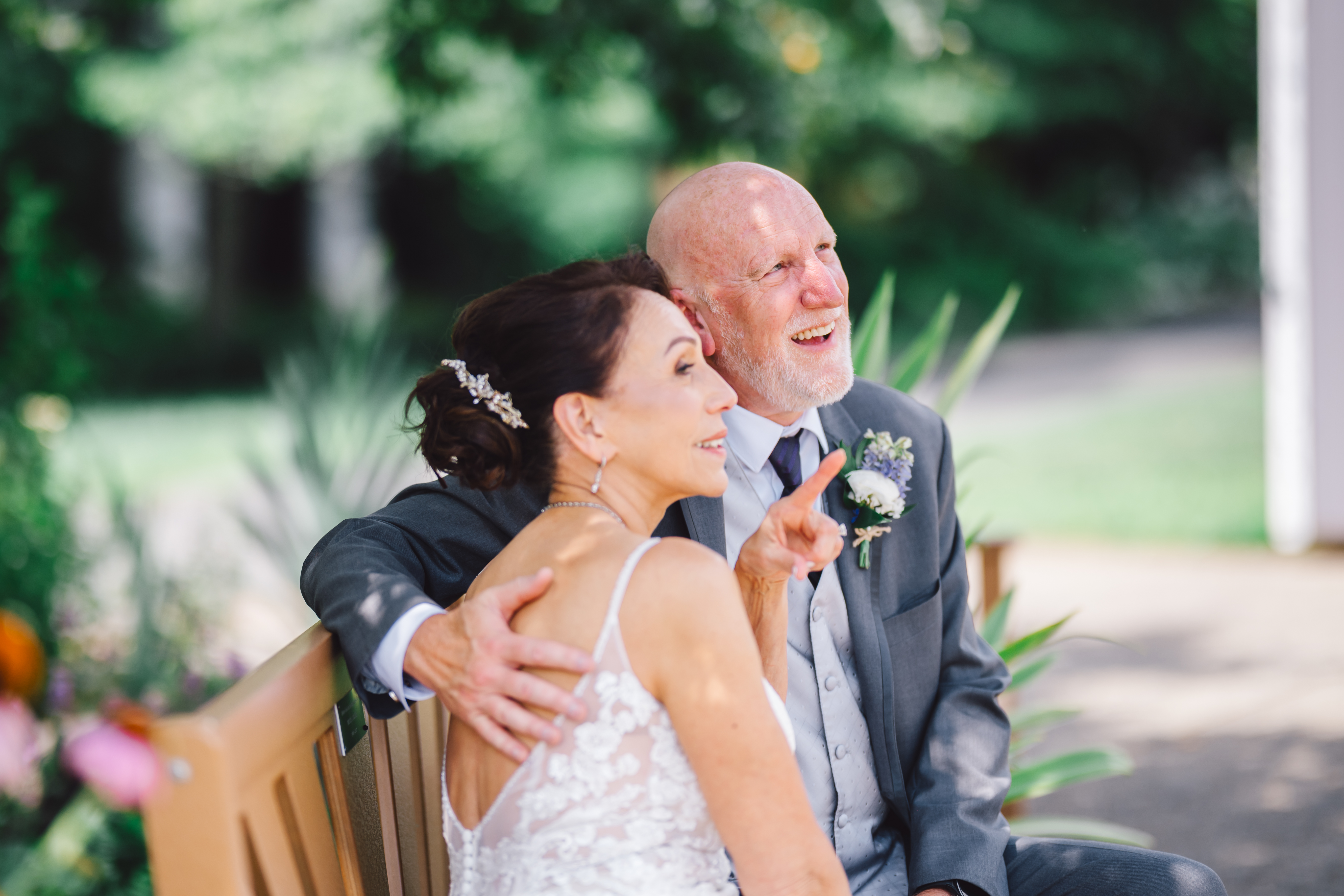 Couple sitting on bench in the Atrium at Meadowlarks garden with bride pointing and admiring
