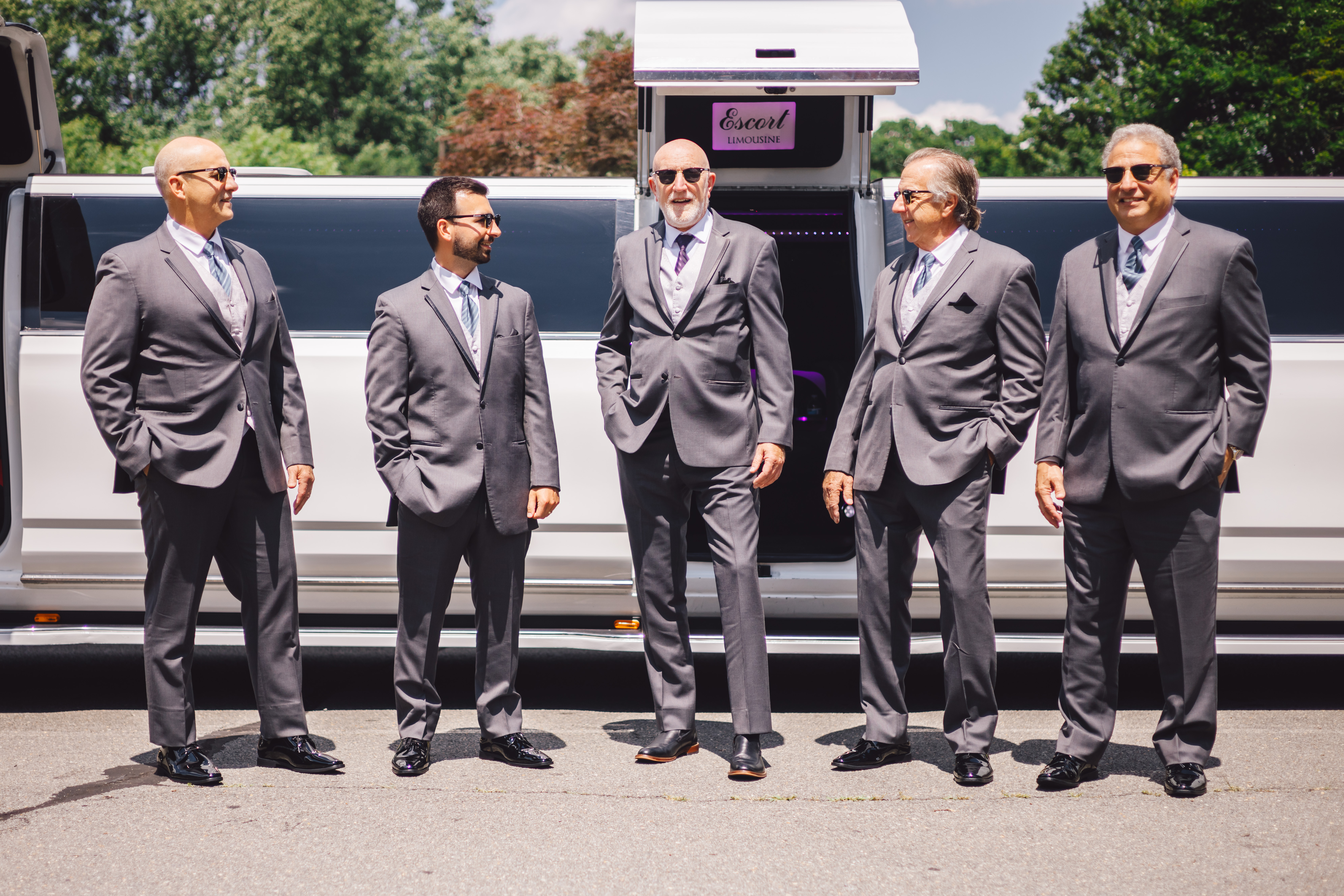 grooms party in front of white stretched limo