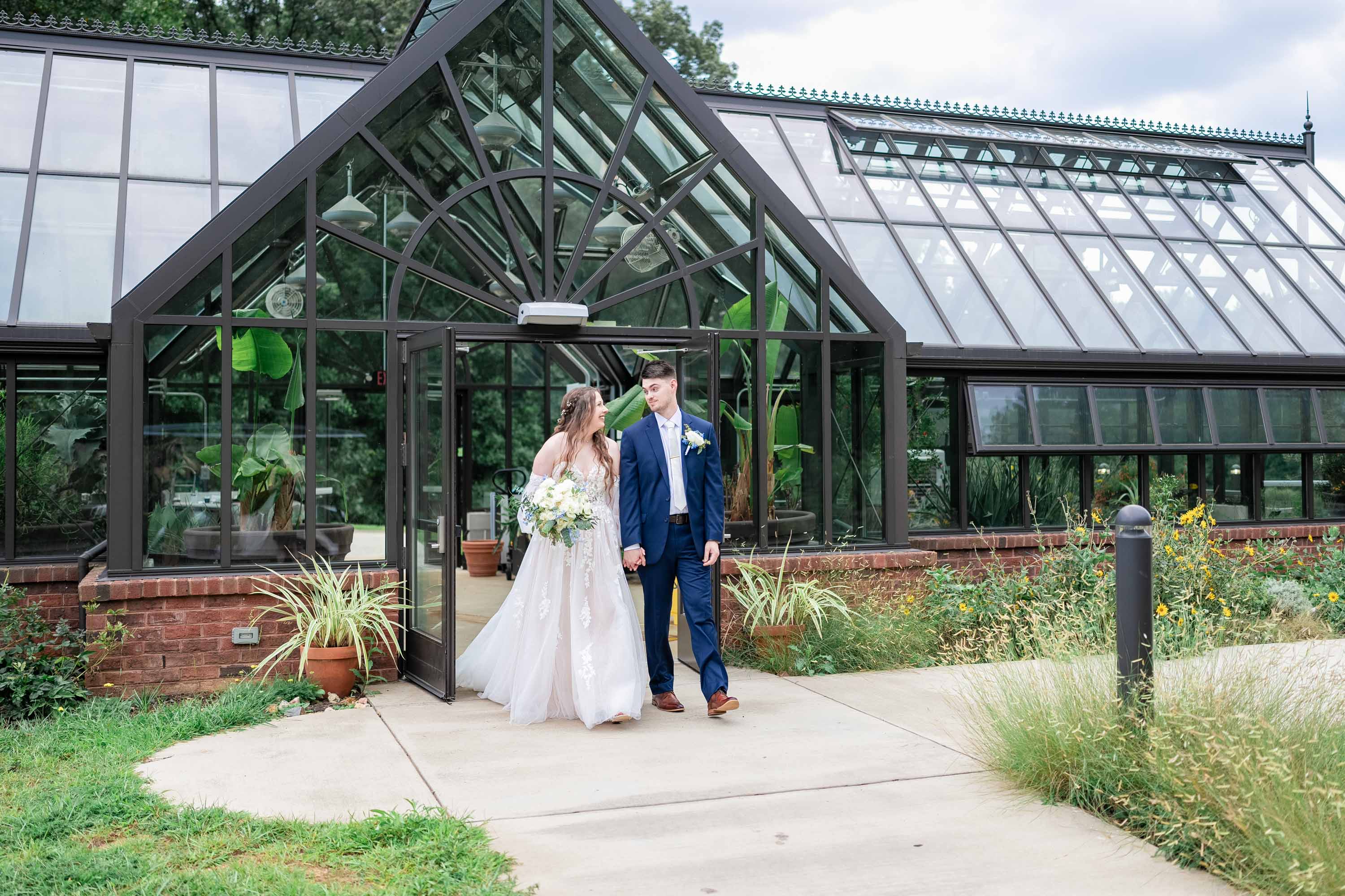 Couple holding hands walking out of greenhouse