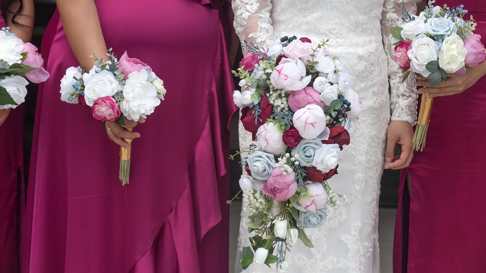 close up of the bride's white dress and bridesmaids' magenta dresses and bouquets