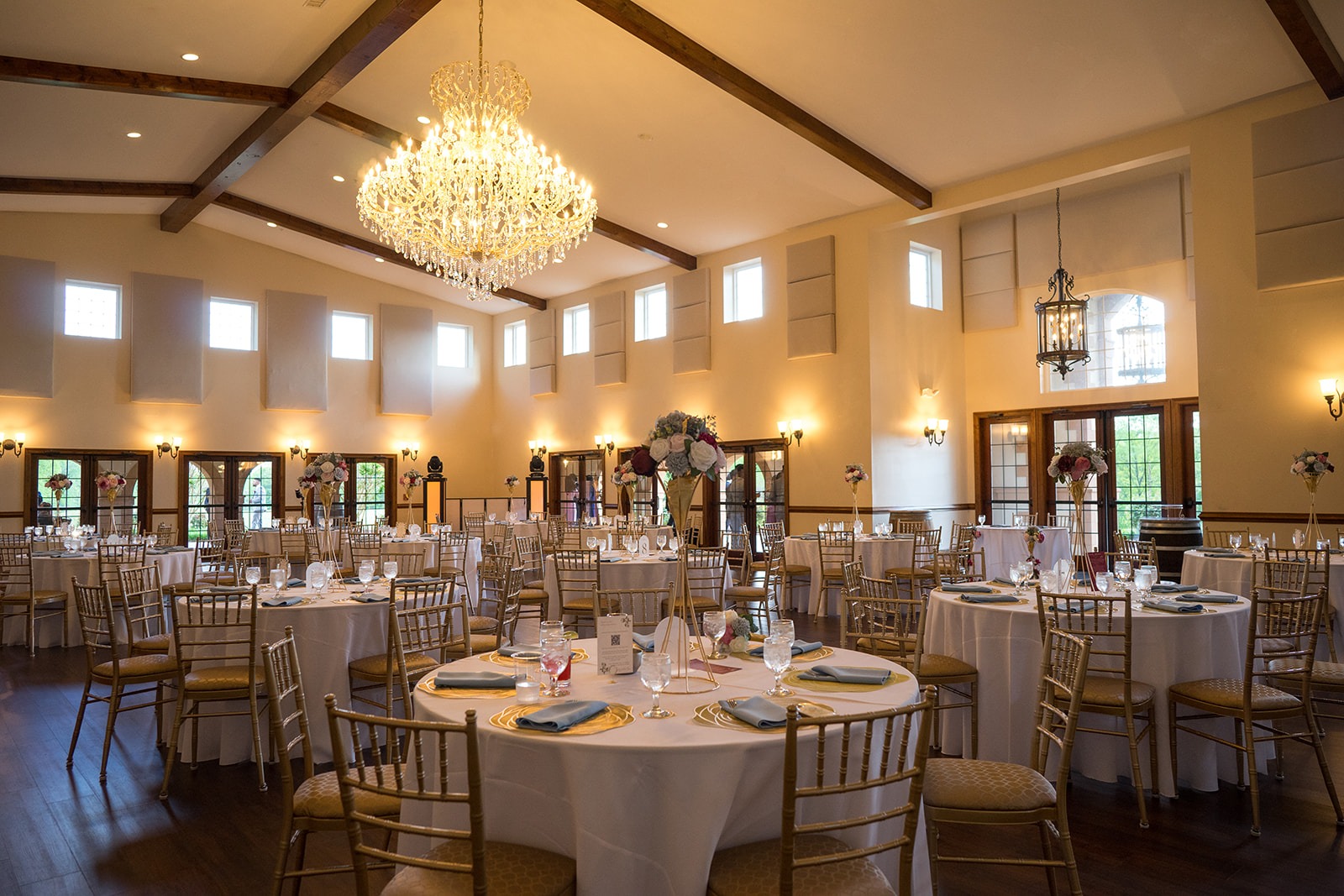 panoramic view of the white, green, and gold table set up for reception in the ballroom with a large chandelier hanging